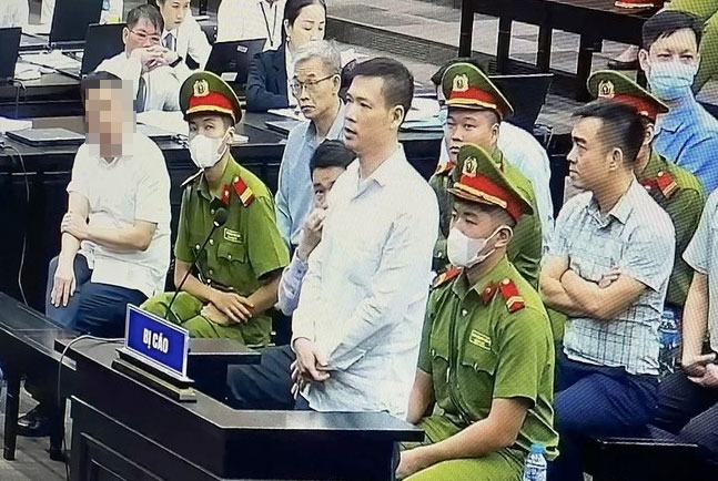 Trần Minh Tuấn (đứng) - người được Nguyễn Xuân Thông bày cách khai báo gian dối, trong suốt quá trình xét xử sơ thẩm vụ án chuyến bay giải cứu (giai đoạn 1) đều cho rằng bị oan. Ảnh chụp qua màn hình tivi: Quang Việt