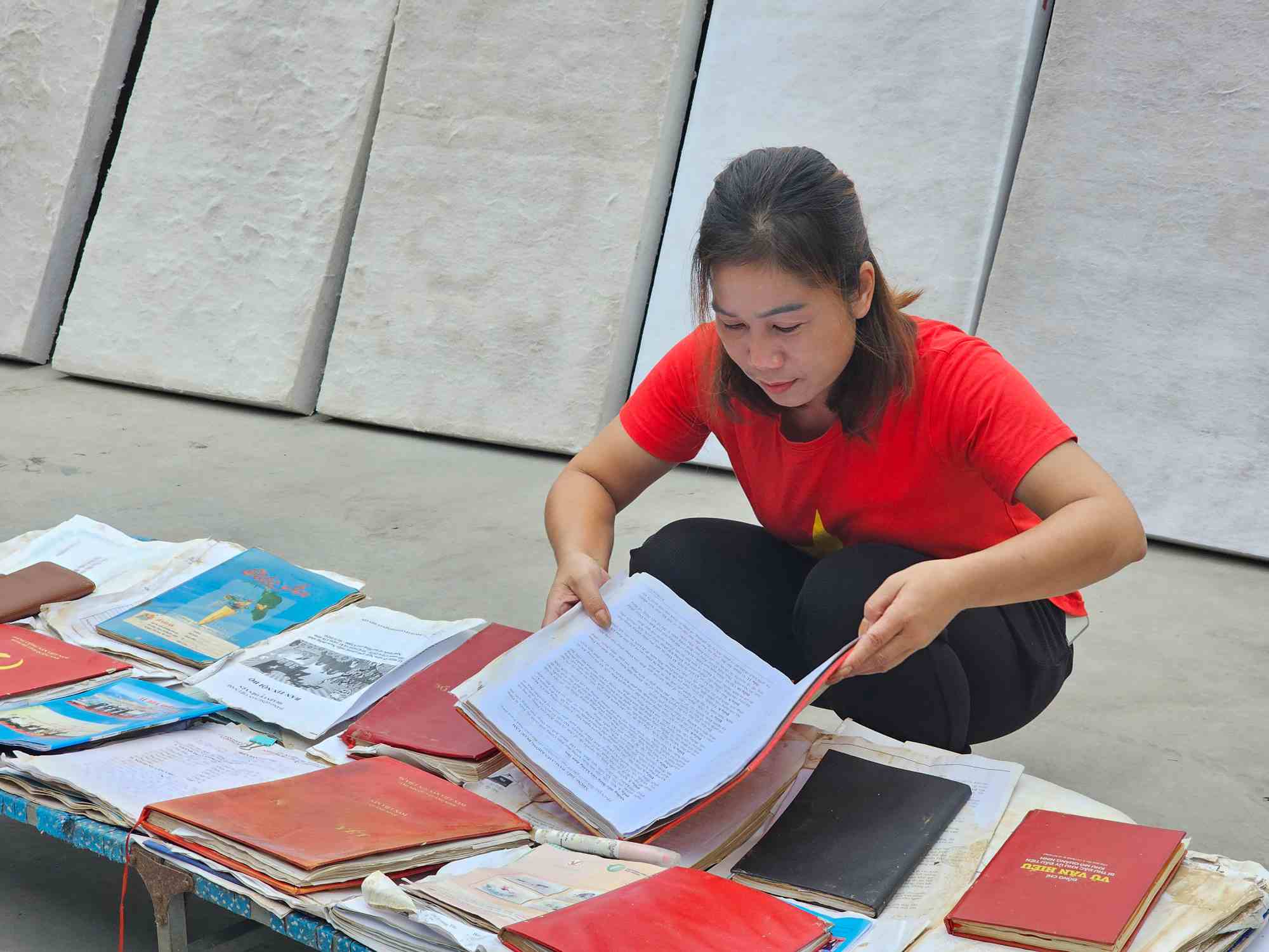 Ms. Nong Thi Tram, Head of Ha Trang Tay Village, Dong Hai Commune, is drying documents and books that were flooded after the storm. Photo: Doan Hung
