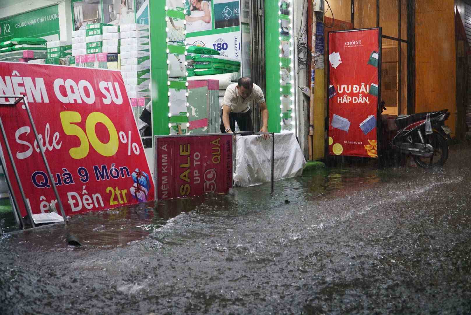 Người dân trên đường Bạch Đằng phải dùng bảng hiệu ngăn nước vào nhà. Ảnh: Minh Quân