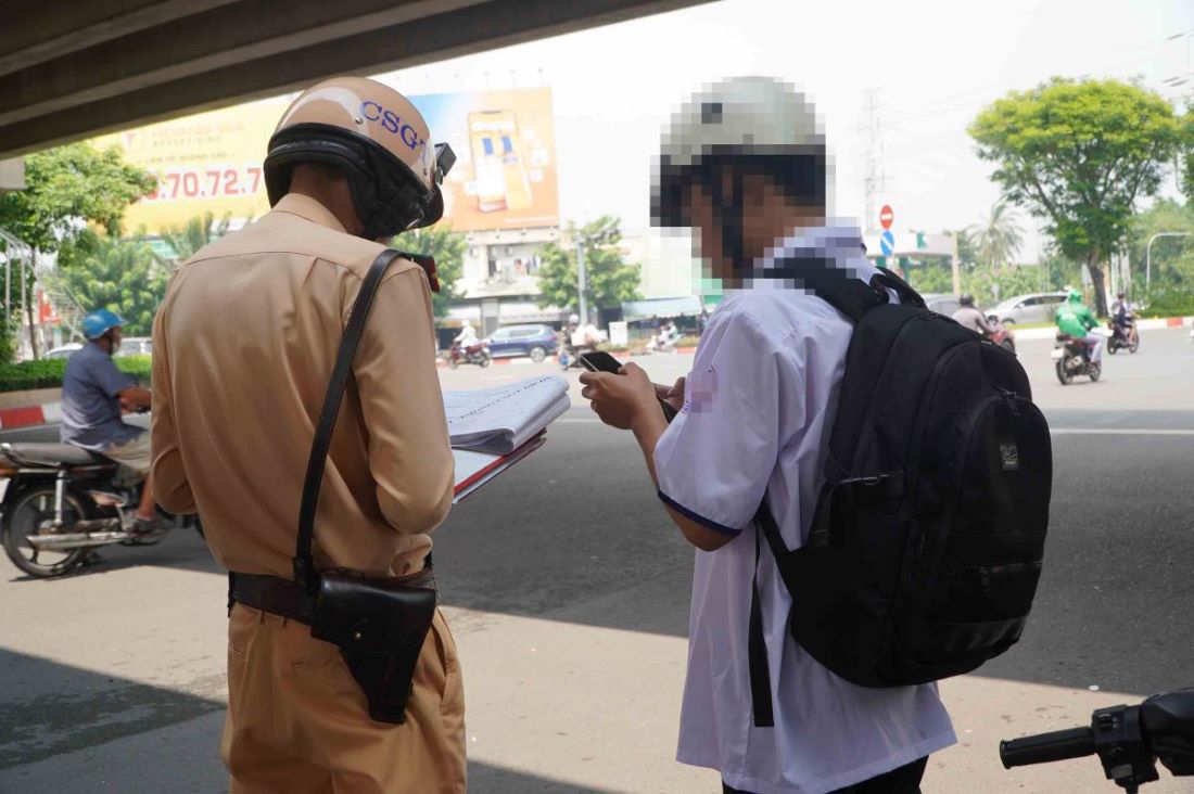 B.M.T - a 10th grade student - was ticketed by the traffic police for driving a motorbike without the required qualifications. Photo: Nguyen Chan