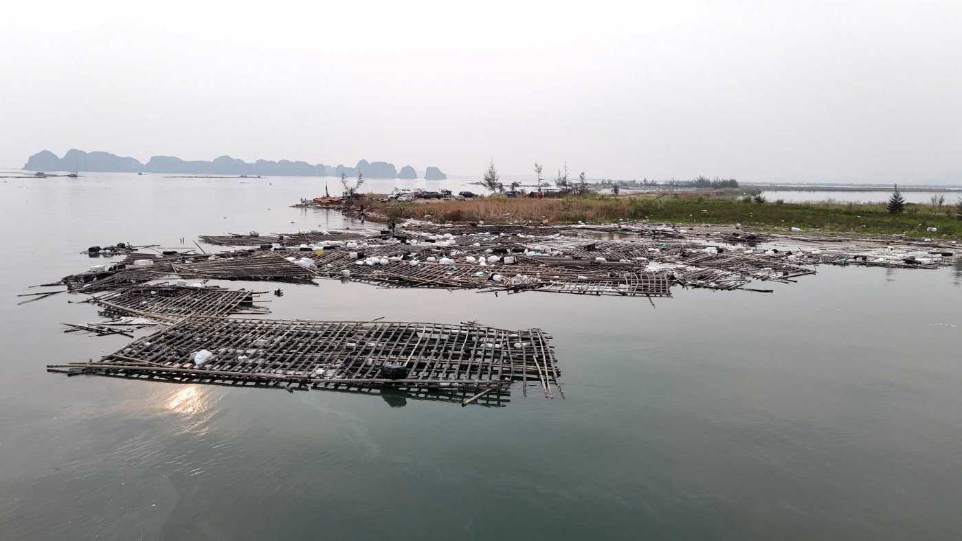 Trash and bamboo rafts drift along the shore of Ha Long Bay. Photo: Duong Hoang