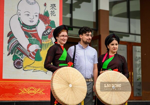 Du khách quốc tế đến tham quan Nhà hát Dân ca Quan họ Bắc Ninh, mặc áo tứ thân, đội nón ba tầm của người quan họ. Ảnh: Vân Trường
