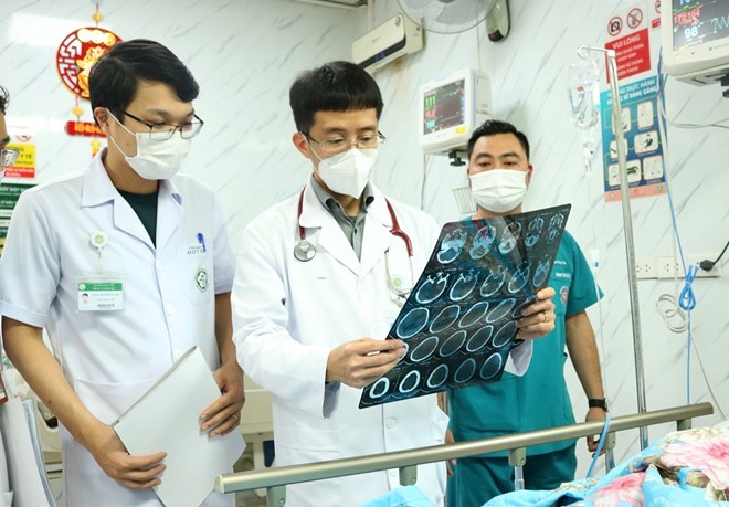 Associate Professor, Dr. Mai Duy Ton (standing in the middle) examines a patient being treated at the Stroke Center - Bach Mai Hospital. Photo: BVCC