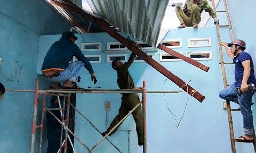 Các lực lượng chức năng ở xã Phổ Thuận, thị xã Đức Phổ, tỉnh Quảng Ngãi giúp hộ dân khắc phục thiệt hại do lốc xoáy làm tốc mái nhà. Ảnh: Đức Minh