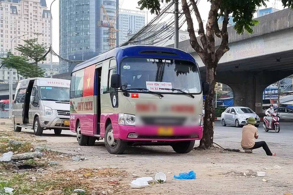Leaving the roadway, passenger buses climb onto the sidewalk in Hanoi