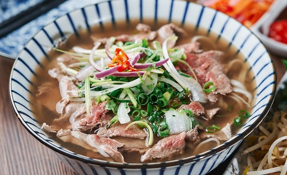 Phở bò tái ăn kèm một số loại rau gia vị. Ảnh: Taste Atlas