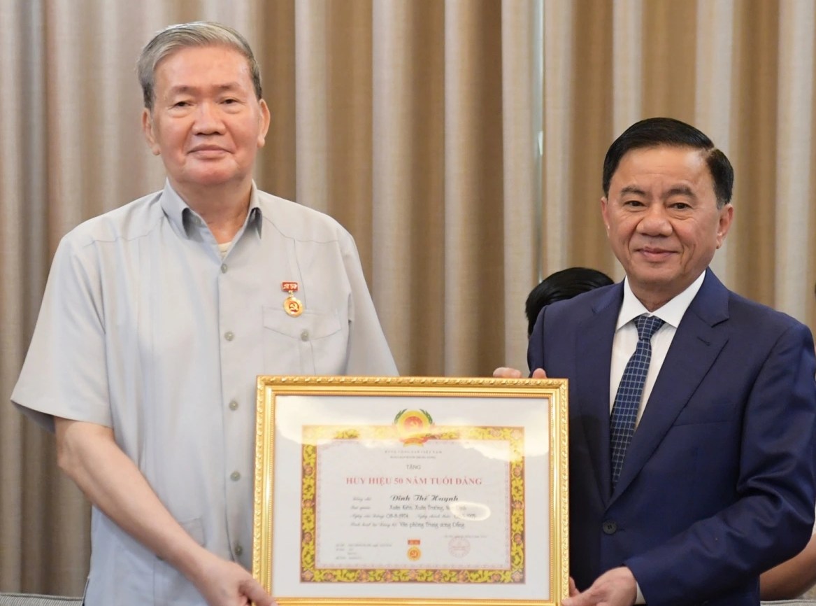 Standing member of the Secretariat and Chairman of the Central Inspection Commission Tran Cam Tu presented the 50-year Party membership badge to former Standing member of the Secretariat Dinh The Huynh. Photo: VOV