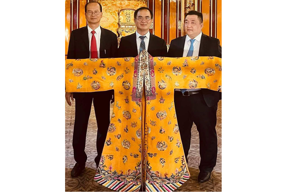 Director of the Hue Monuments Conservation Center (left) and Mr. Tran Phan Anh (middle) with the Nhat Binh dress of Queen Nam Phuong. Photo: Hue Monuments Conservation Center