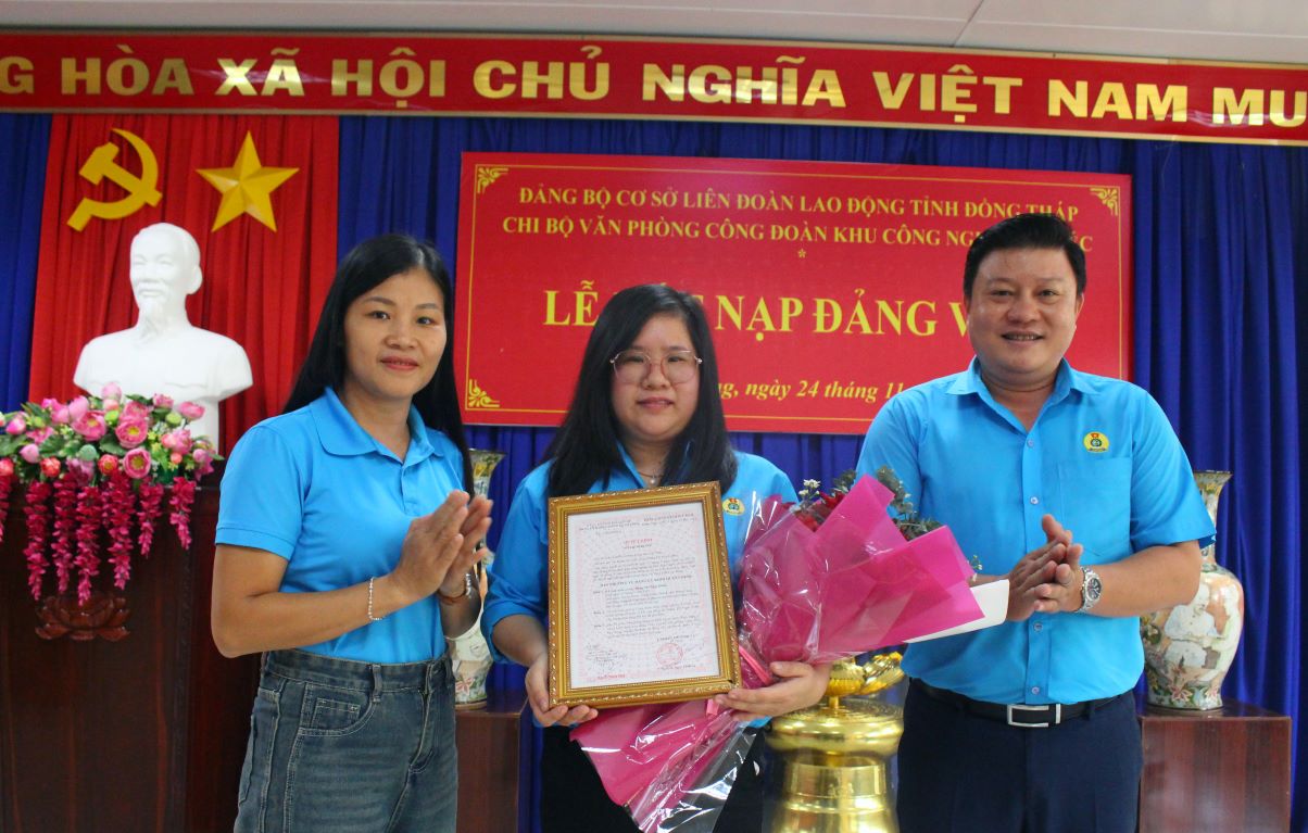 Ba Truong Thi Thuy Linh – Dang uy vien Dang uy co so LDLD tinh Dong Thap cung ong Nguyen Thanh Nhan trao quyet dinh ket nap dang va hoa chuc mung dang vien Dang Thi Ngoc Diem. Anh: Thanh Mai