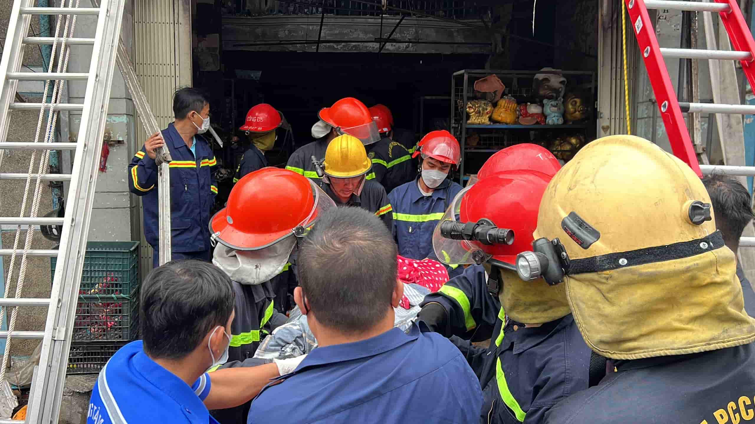 Authorities carry the bodies of the victims of the fire outside. Photo: Huu Long