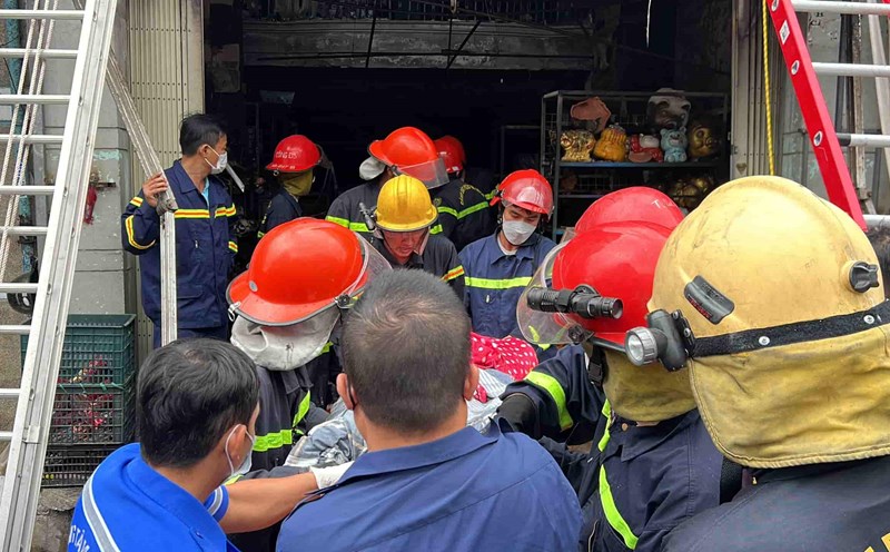 Authorities carry the bodies of the victims of the fire outside. Photo: Huu Long