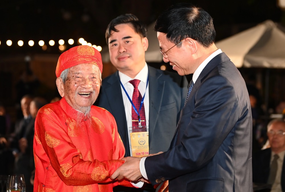 Bo truong Bo Thong tin va Truyen thong Nguyen Manh Hung (bia phai) bat tay nha nghien cuu Nguyen Dinh Tu tai Le trao Giai thuong Sach Quoc gia. Anh: Ban to chuc