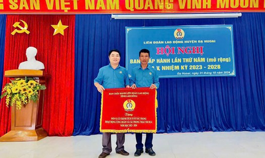 Chủ tịch Liên đoàn Lao động huyện Đạ Huoai – ông Trần Kim Anh (bìa phải) trao cờ thi đua xuất sắc của Liên đoàn Lao động tỉnh Lâm Đồng cho công đoàn cơ sở. Ảnh. THU GIANG