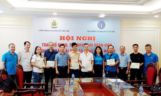 Đại diện Công đoàn ngành GTVT TP Hà Nội, BHXH quận Tây Hồ và Nghiệp đoàn Lái xe ôtô công nghệ Hà Nội trao thẻ BHYT và sổ BHXH cho đoàn viên. Ảnh: CĐCS