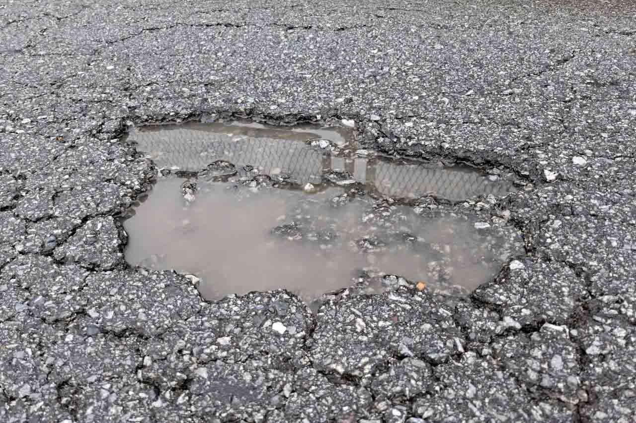 Mặt đường nứt mai rùa, bong tróc tạo thành ổ voi. Ảnh: Trần Tuấn.