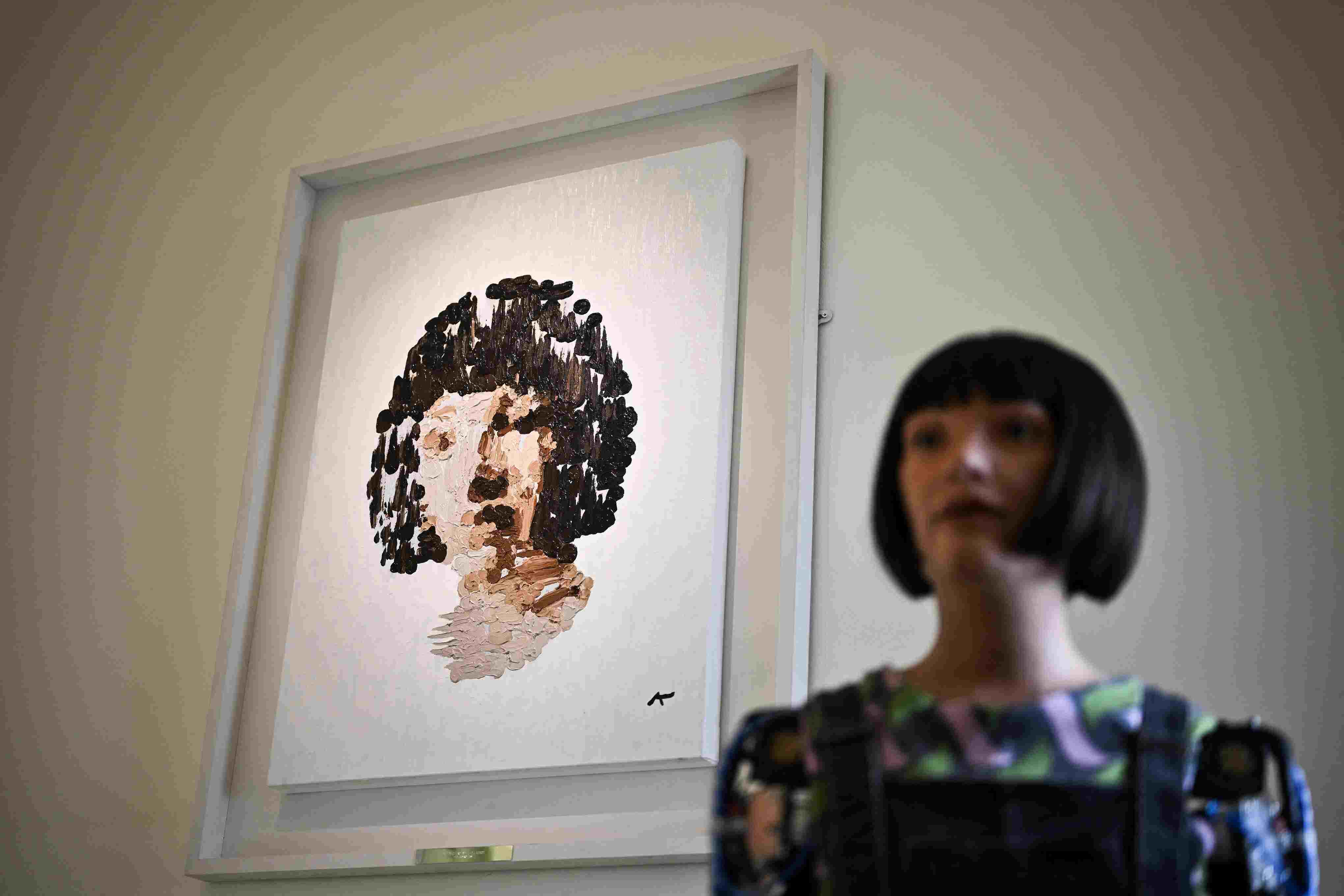 Ai-Da robot and the painting worth 1.3 million USD. Photo: AFP