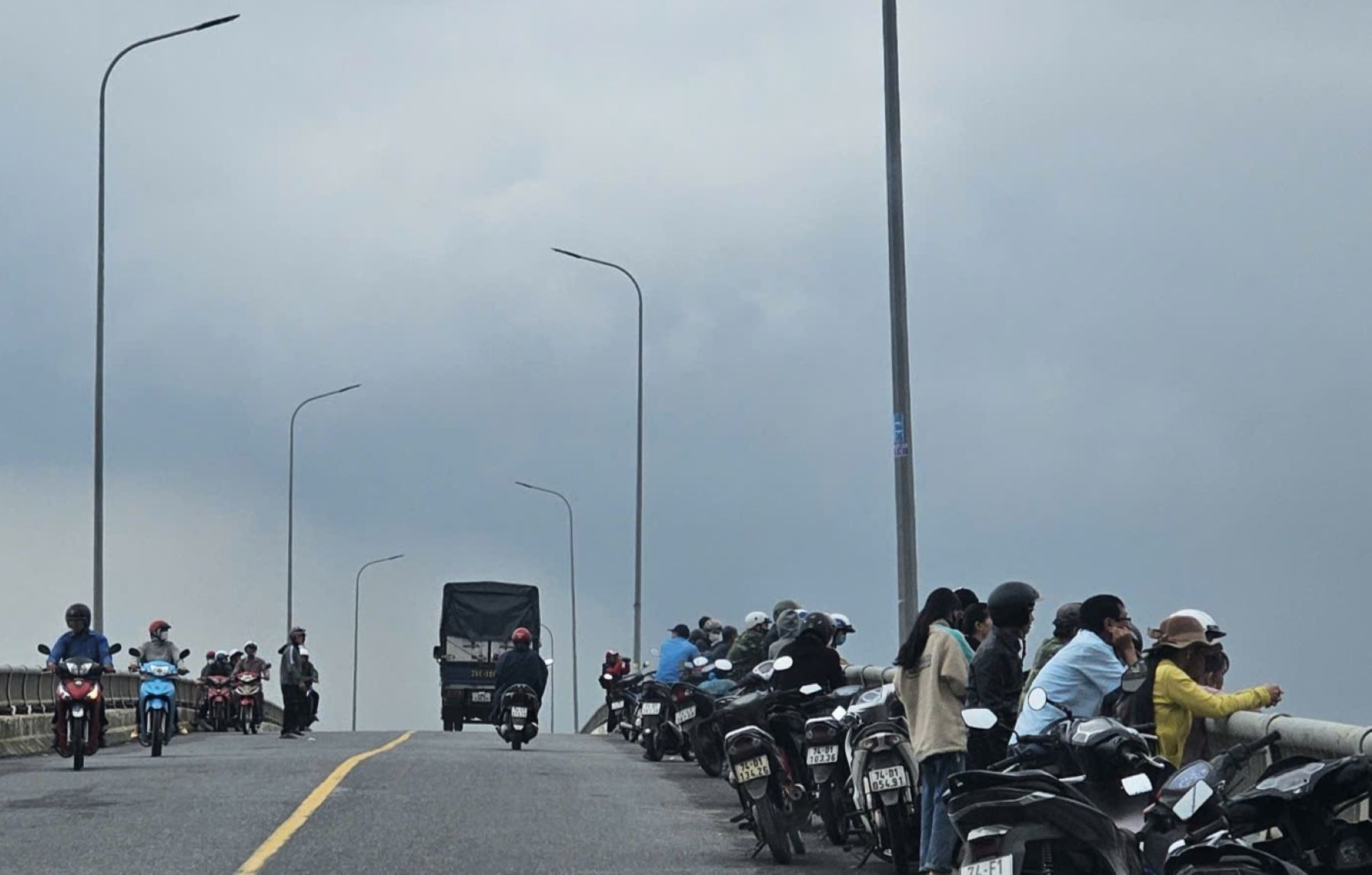 People standing on the bridge watching the search forces for the missing woman. Photo: H.Nguyen