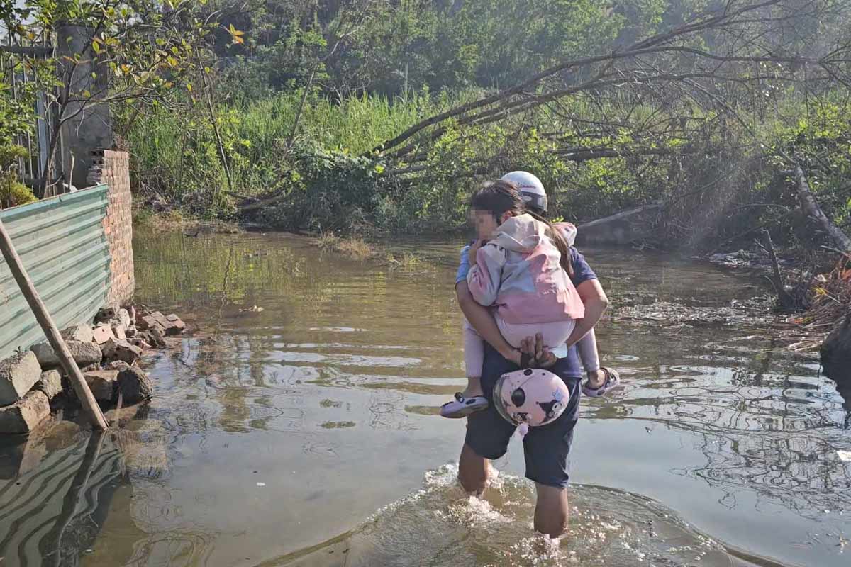 People wade through water to take their children to school during high tide in Ha Long City, Quang Ninh Province. Photo: Doan Hung
