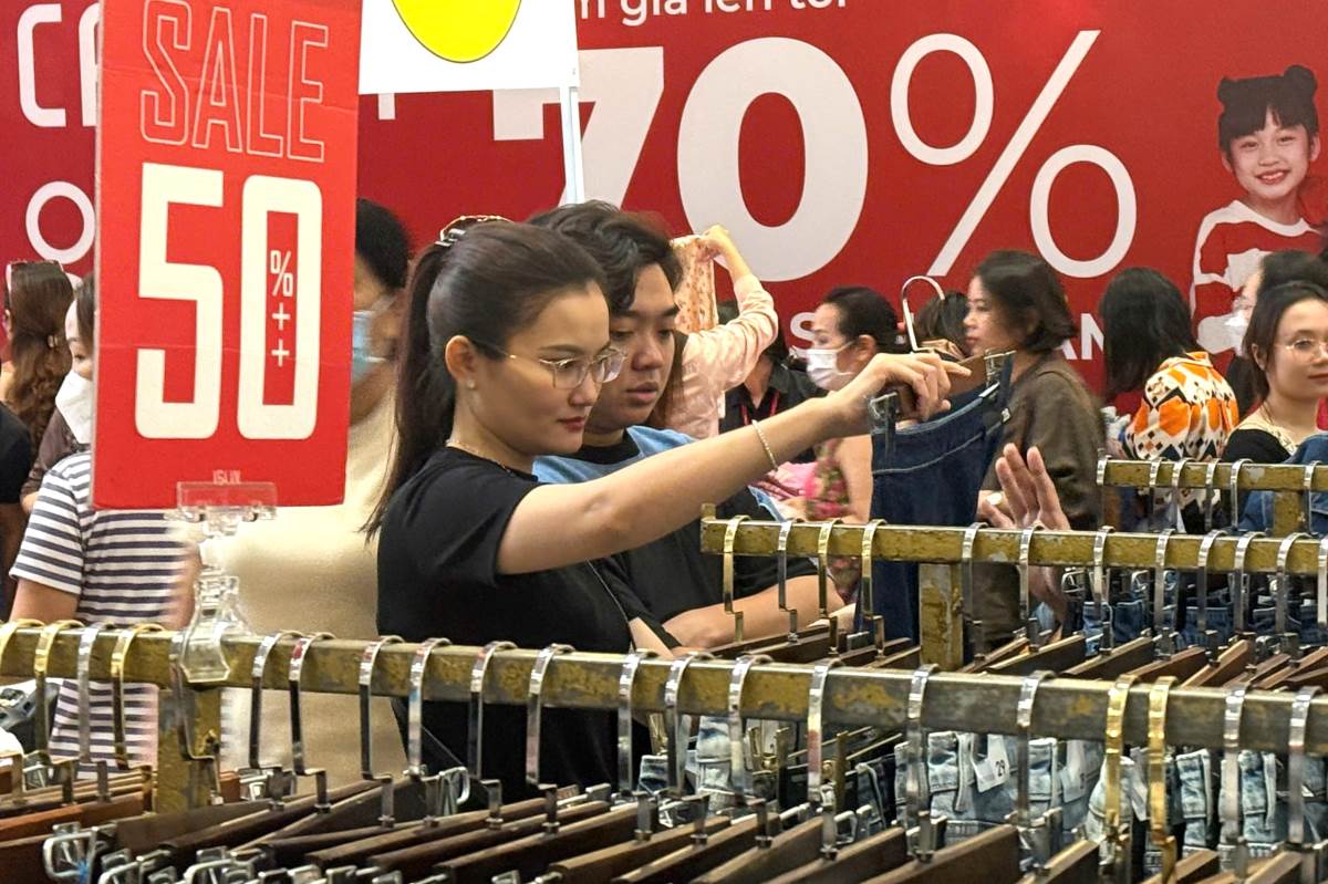 Chị Phương Thủy xem hàng hóa được bày bán trong sự kiện khuyến mãi hàng hiệu. Ảnh: Thành An