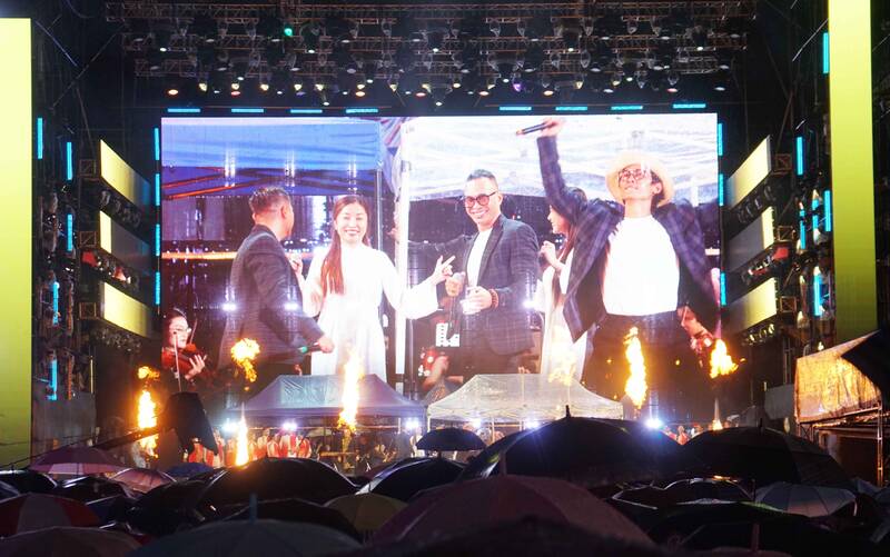 People wearing raincoats and holding umbrellas watch the festival. Photo: Le Chan