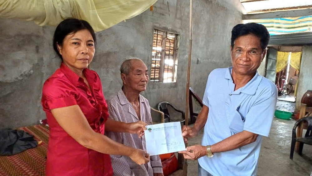 Mr. Danh Huong (nearly 100 years old, Khmer ethnic group) was supported and guided by Mr. Lam to complete the procedures to receive the subsidy. Photo: Xuan Nhi