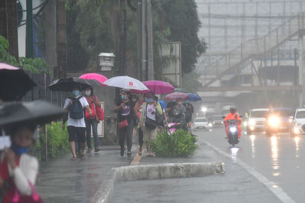 Rain falls on pedestrians in Quezon City, Philippines. Photo: ABS