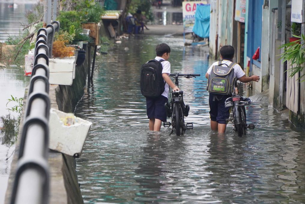 2 em hoc sinh buoc phai xuong dat bo xe di qua doan duong ngap de dam bao an toan.