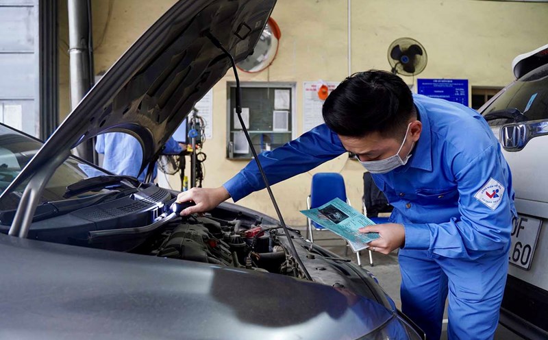 Staff performing vehicle inspection in Hanoi. Photo: Huu Chanh