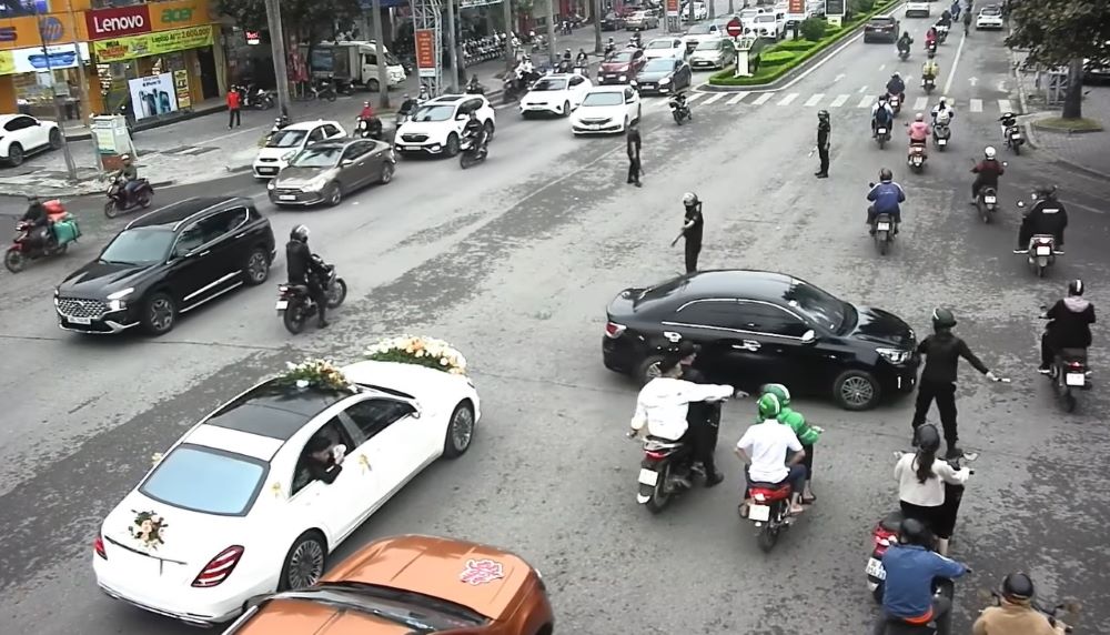 The image captures the scene of a group of bodyguards in the middle of the road directing traffic for the wedding procession to pass. Photo cut from clip.