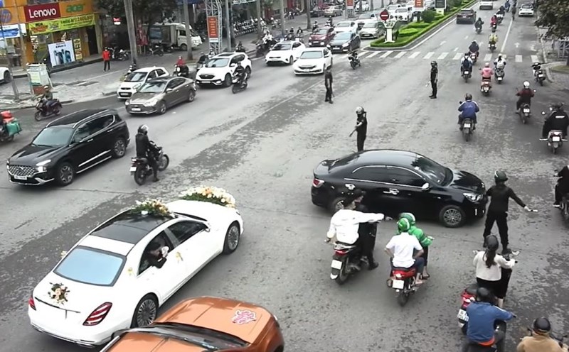 The image captures the scene of a group of bodyguards in the middle of the road directing traffic for the wedding procession to pass. Photo cut from clip.