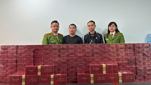 Hai đối tượng kinh doanh thuốc lá điếu nhập lậu (áo đen ở giữa) bị cơ quan Công an bắt giữ cùng số thuốc lá điếu nhập lậu. Ảnh: CA cung cấp