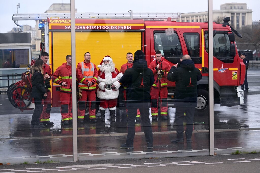 Firefighters take a photo with Santa Claus near the Eiffel Tower after responding to a fire on December 24. Photo: AFP