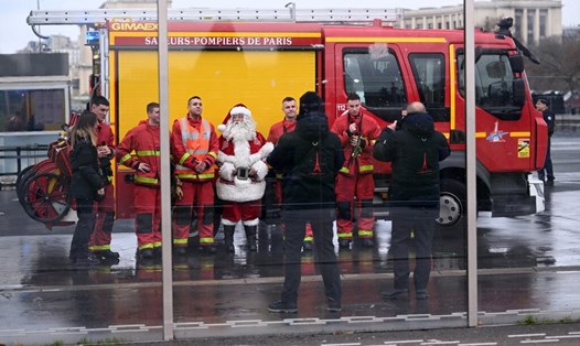 Lính cứu hỏa chụp ảnh với ông già Noel gần tháp Eiffel khi ghi nhận đám cháy ngày 24.12. Ảnh: AFP