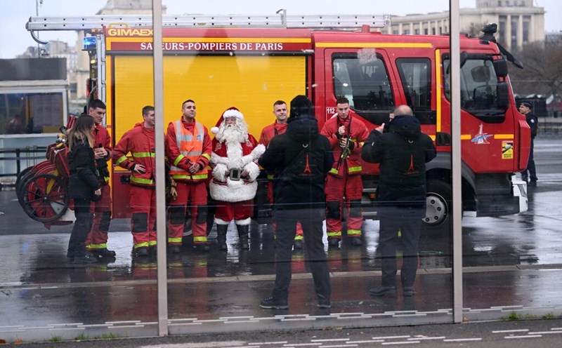 Firefighters take a photo with Santa Claus near the Eiffel Tower after responding to a fire on December 24. Photo: AFP