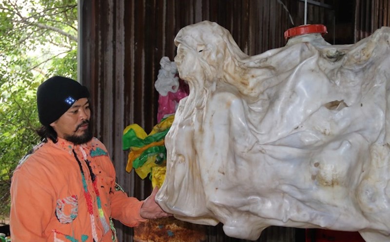 Painter Nguyen Quoc Dan with his artworks in Hoi An. Photo: Nguyen Linh