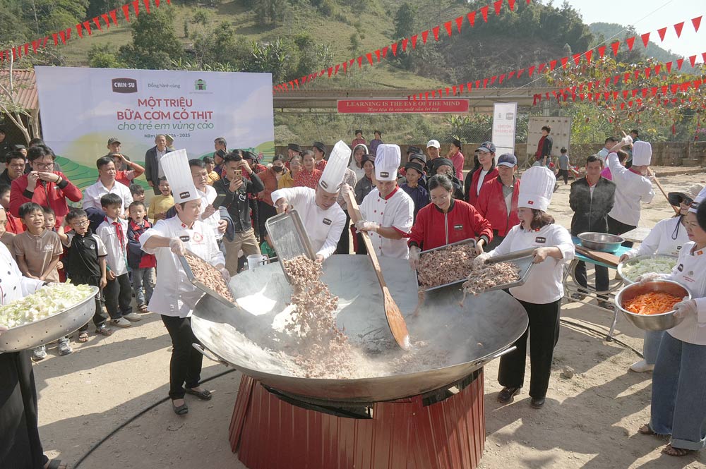 Students eagerly wait in front of a giant pan of rice with meat. Photo: H. Van