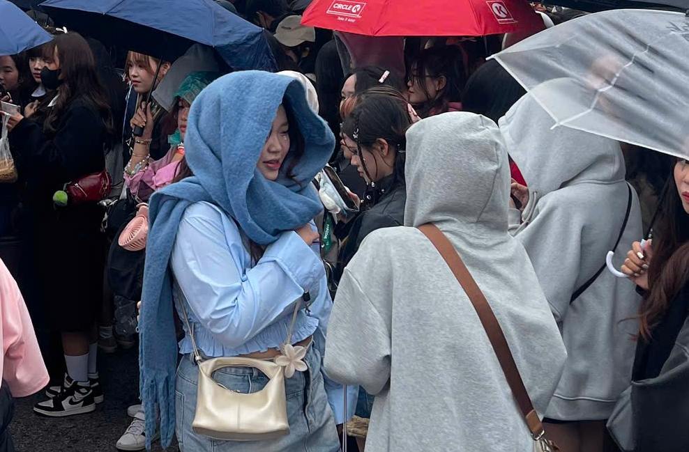 Audience members wear hats and hold umbrellas in the cold and rainy weather in Hanoi before the concert "Anh trai say hi". Photo: Hoang Hue