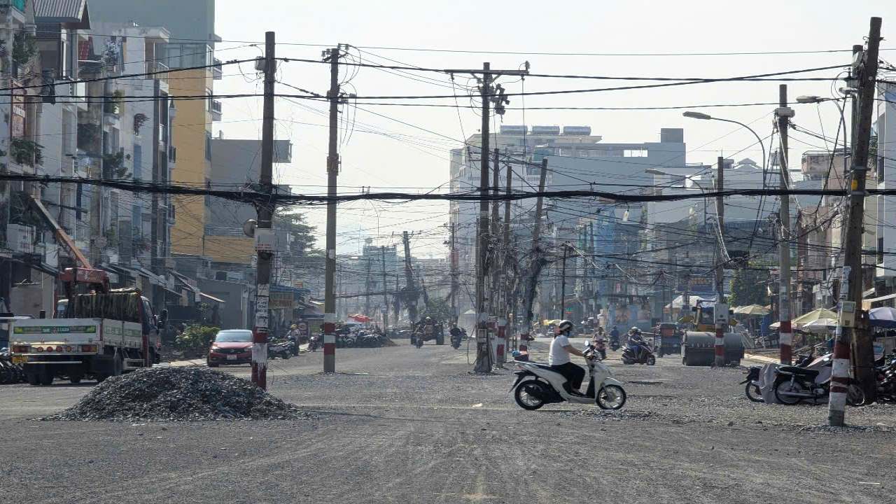 Hien hang tram cay cot dien van con ngon ngang ngay giua cong trinh va hai ben duong chua duoc di doi. Anh: Anh Tu  