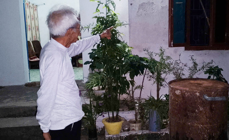 Mr. Dang - a revolutionary contributor - points to the damaged walls that were patched up temporarily after spending his own money to repair them. Photo: Manh Cuong.