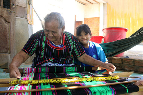 Bà H'Bạch dù năm nay đã 74 tuổi nhưng vẫn thường xuyên chỉ dạy cho con cháu giữ gìn nghề dệt thổ cẩm truyền thống cho gia đình. Ảnh: Phan Tuấn