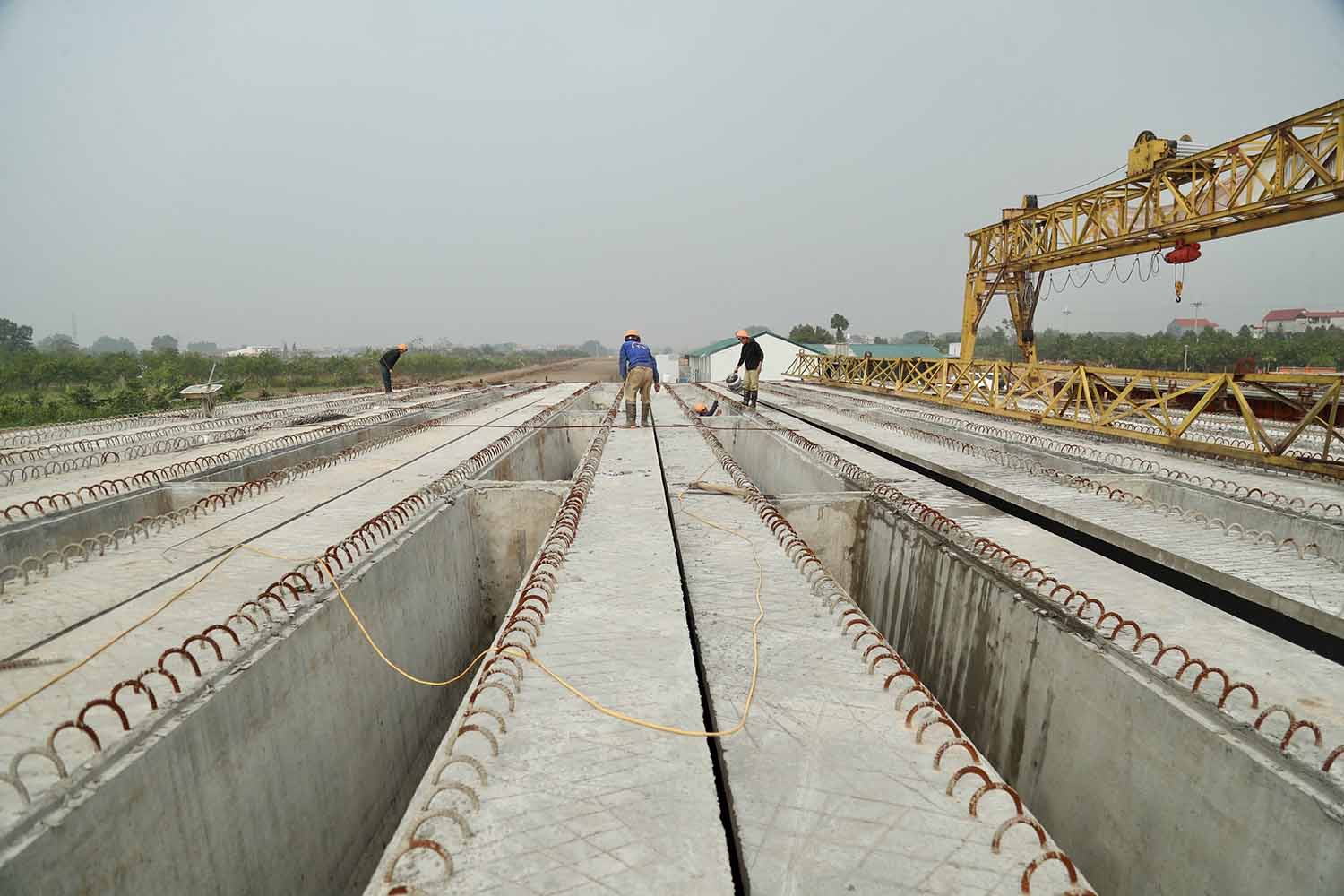 Tại gói thầu số 8 qua huyện Mê Linh, các công nhân đang tiến hành thi công hạng mục dầm cầu vượt qua đường sắt. Ảnh: Hữu Chánh