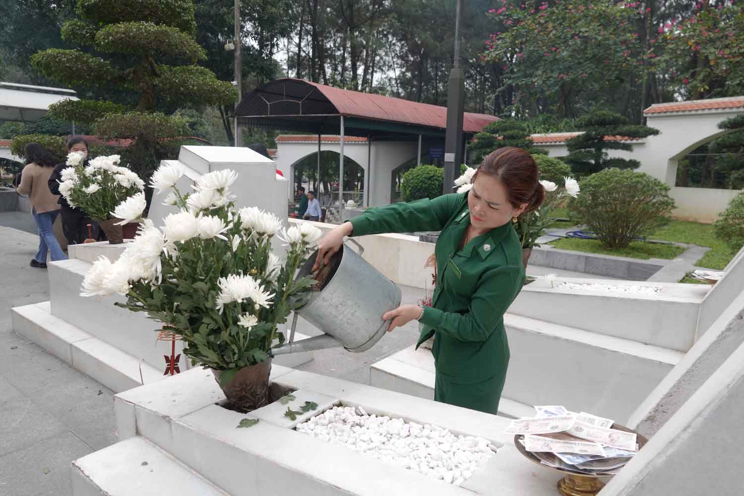 Nhân viên Ban Quản lý Di tích Ngã ba Đồng Lộc tưới nước để hoa trên 10 phần mộ được tươi. Ảnh: Trần Tuấn.