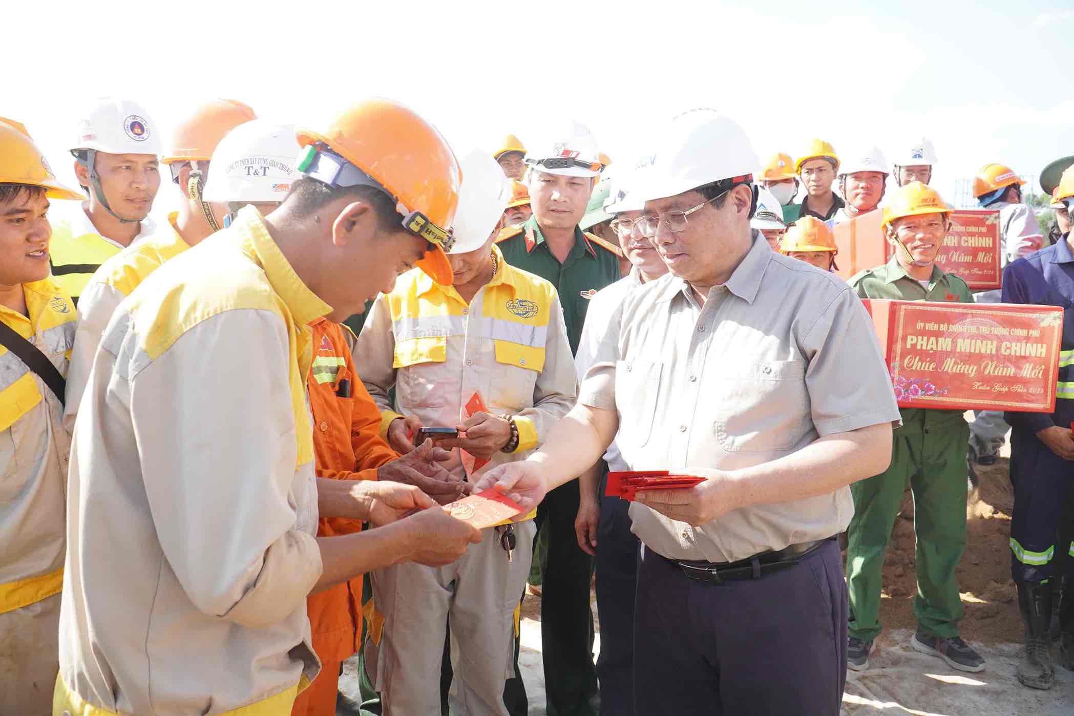 Thủ tướng Phạm Minh Chính lì xì đầu năm mới cho công nhân lao động đang thi công xuyên Tết trên cao tốc Biên Hoà - Vũng Tàu. Ảnh: Hà Anh Chiến