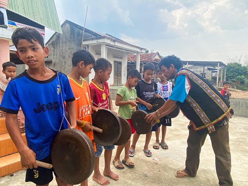 Trẻ em làng O tập luyện đánh cồng chiêng dưới sự hướng dẫn của già làng, trưởng bản. Ảnh: Thanh Tuấn 