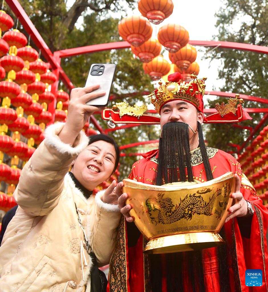 “Thần Tài” chụp ảnh với một khách du lịch ở Lạc Dương, tỉnh Hà Nam, Trung Quốc ngày 14.2.2024. Ảnh: Xinhua