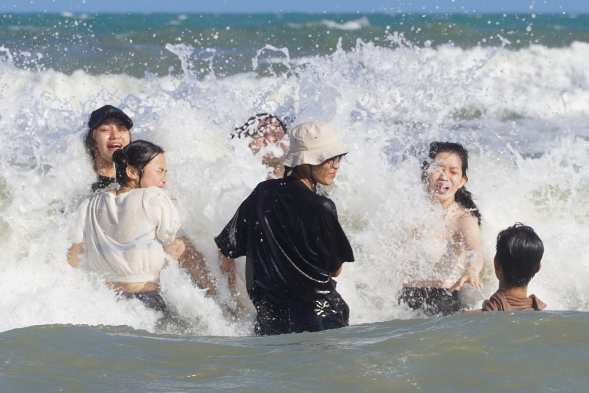 Biển sóng lớn tạo hưng phấn cho nhóm bạn trẻ vui đùa. Ảnh: Thành An 