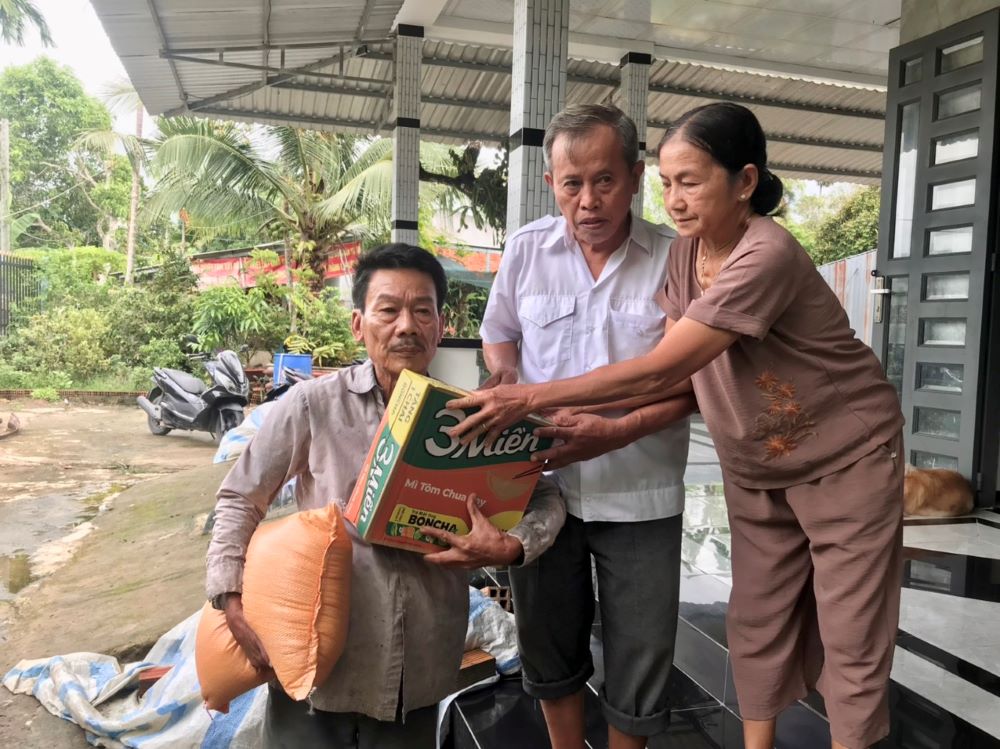 Vợ chồng ông Hai Nùng trao gạo hỗ trợ cho người nghèo ở địa phương. Ảnh: Tạ Quang