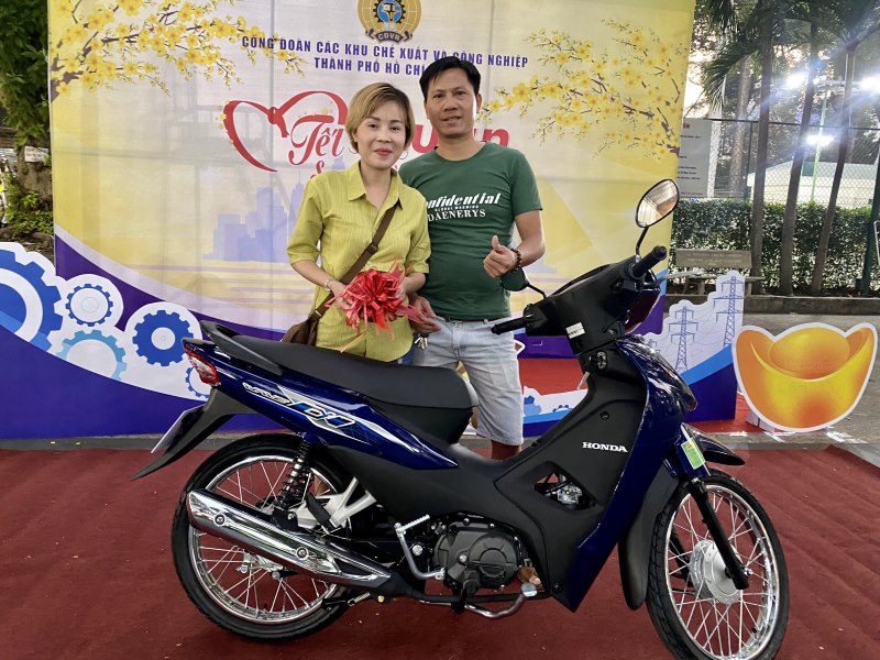 Vợ chồng chị Võ Thị Chiêu Kha vui mừng bên chiếc xe máy trúng thưởng. Ảnh: Đức Long