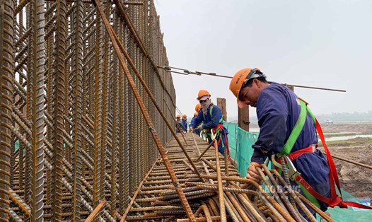 Công nhân đội mưa thi công cầu gần 1.500 tỉ nối Nam Định - Ninh Bình ngày cận Tết. Ảnh: Lương Hà