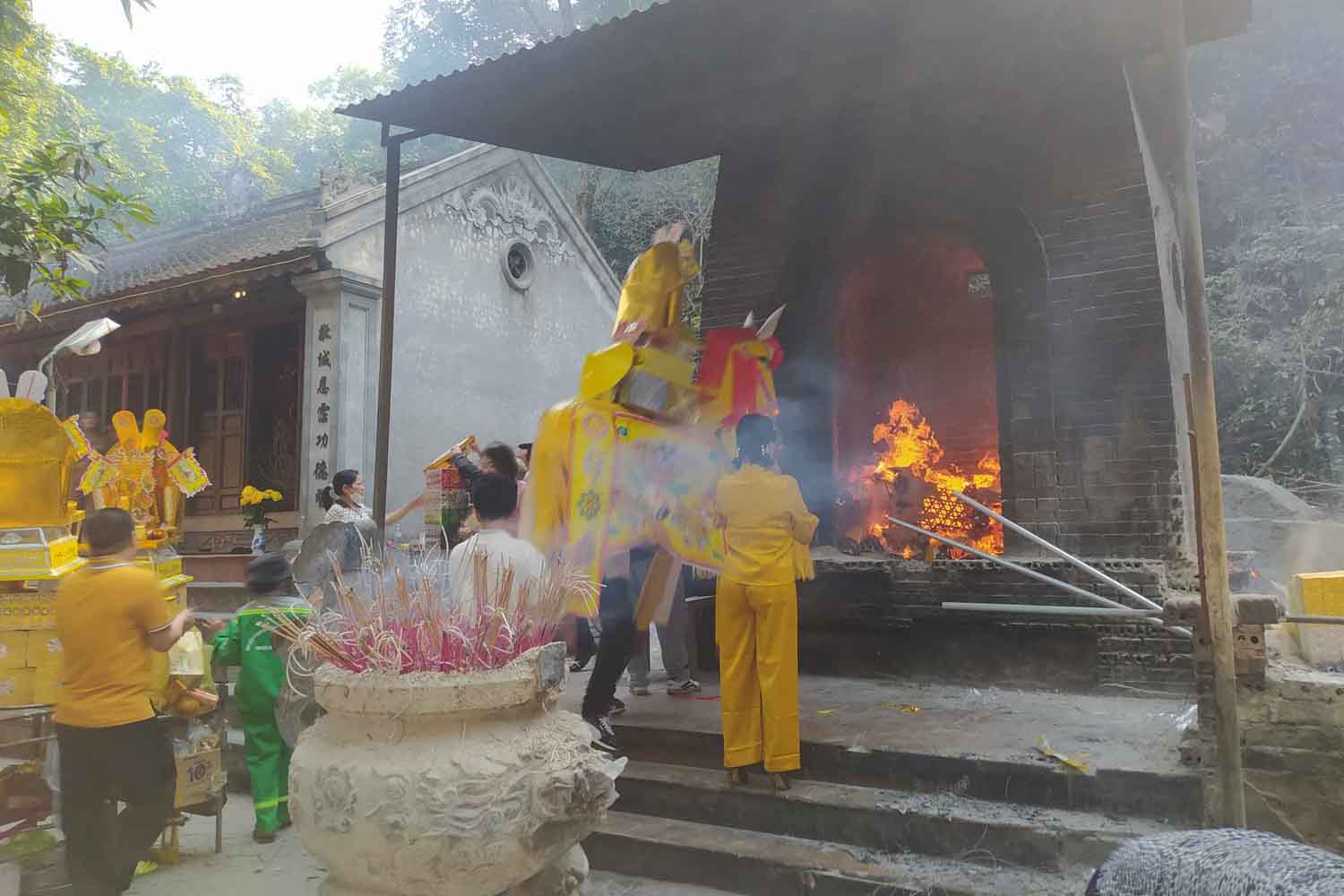 Du khách mang ngựa giấy vào lò đốt sau khi đã dâng cúng cầu may. Ảnh: Trần Tuấn.